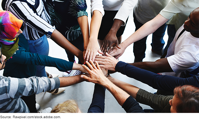 A diverse group of people standing in a circle, each with one hand outstretched to the center