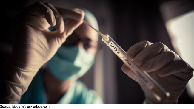 person wearing gloves holding a COVID-19 diagnostic test swab and container