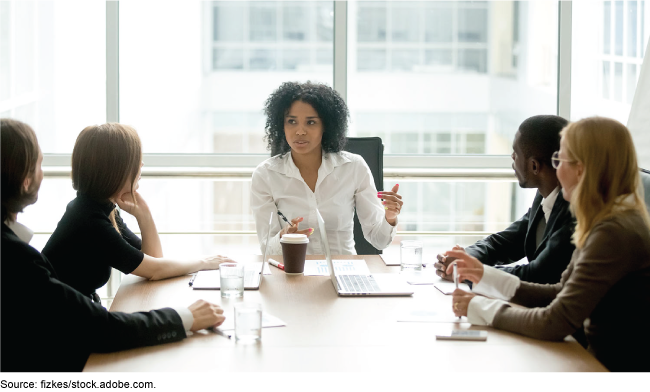 Woman speaking at the head of a table in an office setting