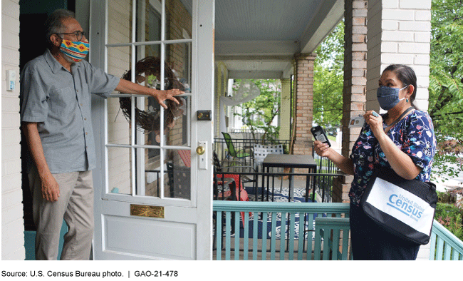 A Census employee using a handheld device to conduct an interview with a male respondent.