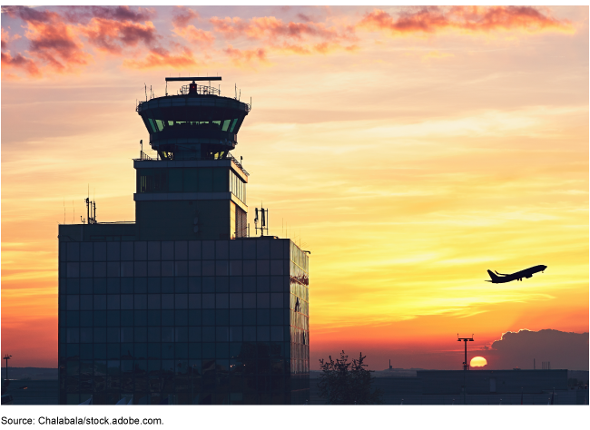 A plane taking off behind an air traffic control tower