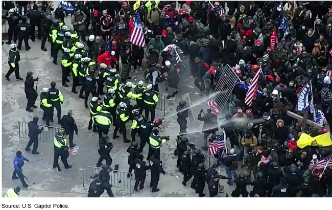 aerial view of police spraying a chemical into a large crowd