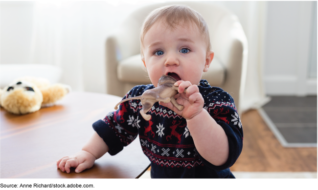 Toddler looking up while opening their mouth to chew on a lion toy. 