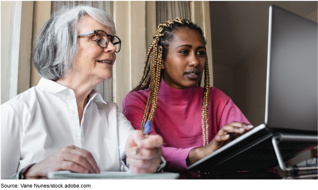 A picture of two people indoors looking at computer.