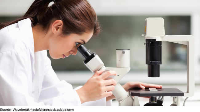 A medical professional looking through a microscope