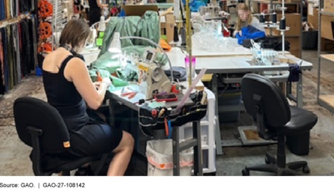 People repairing outdoor textile apparel at tables with sewing machines, fabric, work lights, and various hand tools.