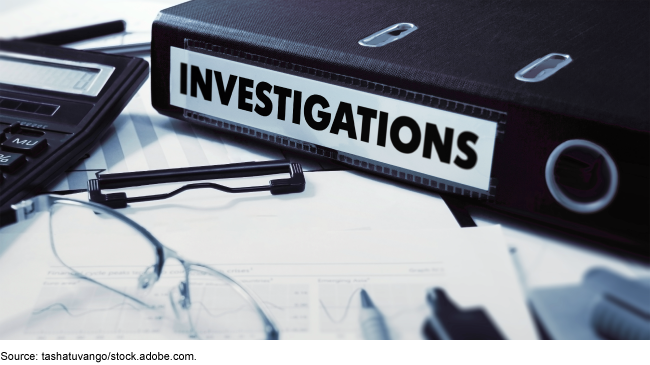 A binder that says investigations on a desk with office supplies and documents.