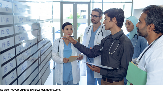 Medical professionals standing in front of a dry erase board