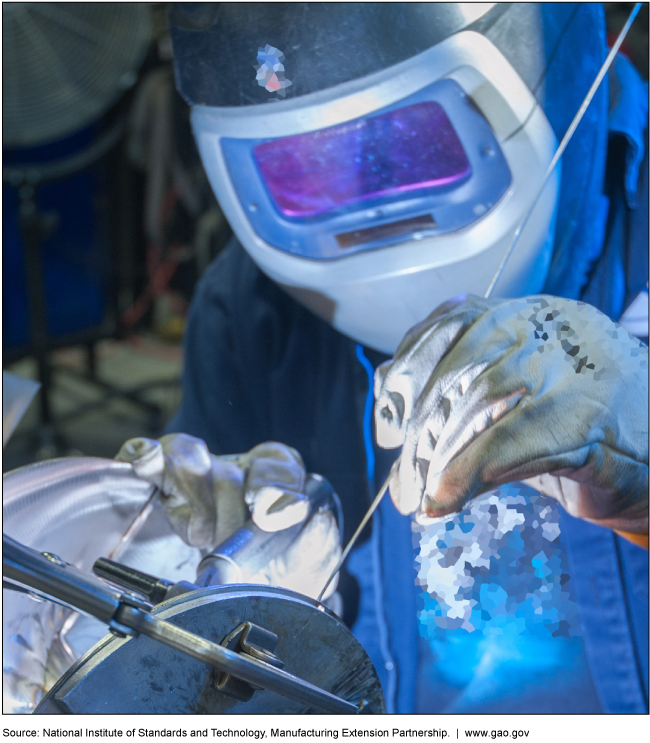 A person wearing a protective suit and operating a metal fabrication machine 