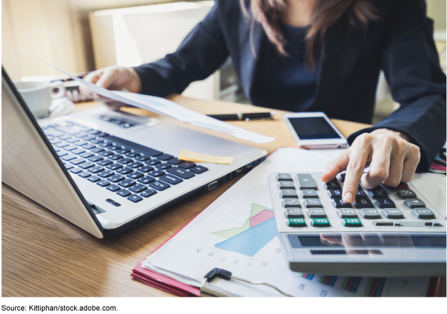 Person working at a desk with a laptop and calculator 