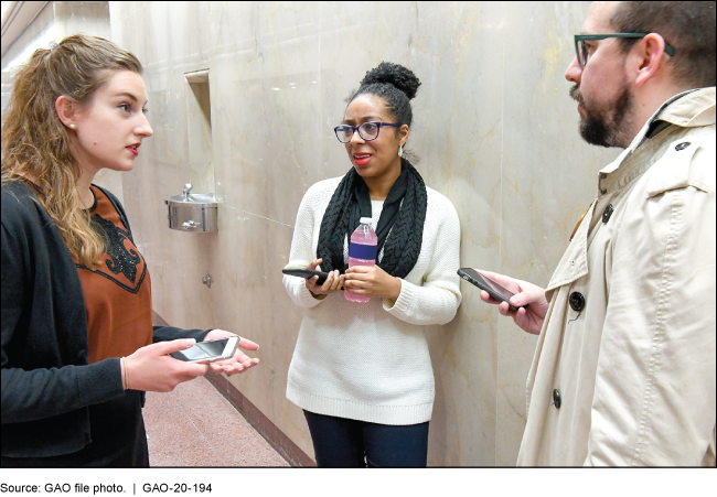 A group of people talking against a wall