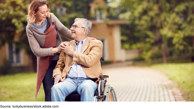 A woman interacts with a man in a wheelchair.