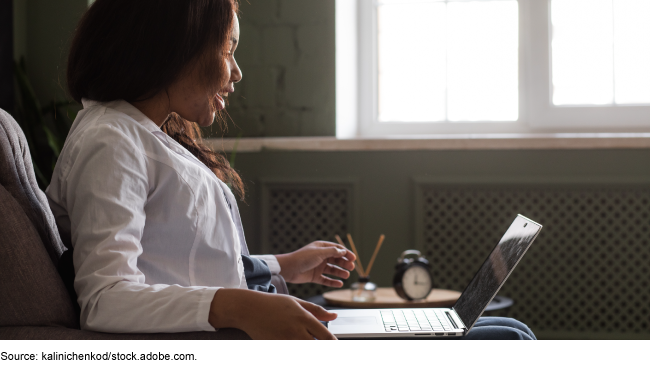 A person sitting in a chair with a laptop in their lap looking at the computer screen with a surprised-happy expression A person sitting in a chair with a laptop in their lap looking at the computer screen with a surprised-happy expression