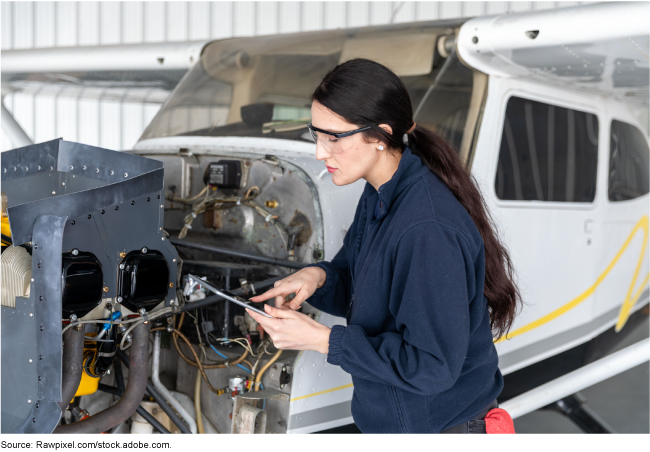 A female mechanic wearing safety glasses standing next to an aircraft. A female mechanic wearing safety glasses standing next to an aircraft.