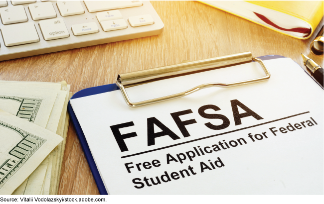Free Application for Federal Student Aid on a desk with computer keyboard and money for college.