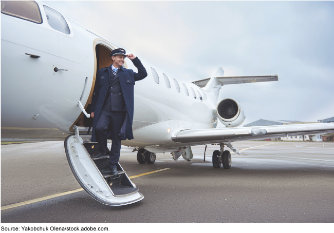 A small regional airplane on the tarmac with a pilot standing on steps leading to the open door for boarding.