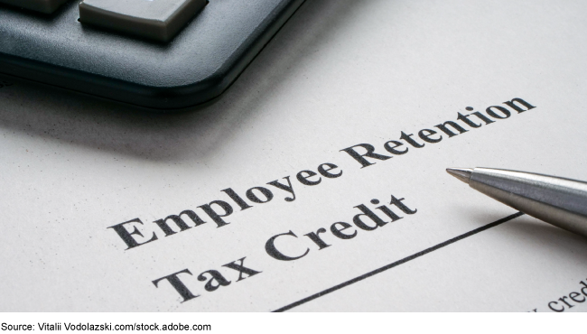 A calculator and pen lay on a paper with the writing 'Employee Retention Tax Credit.'