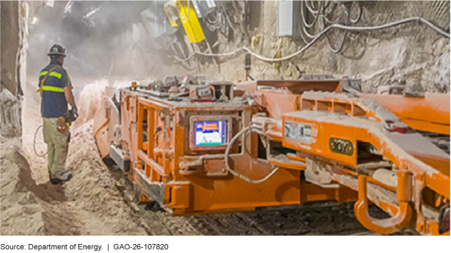 A person stands in an underground salt cavern next to equipment.