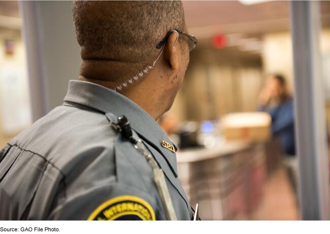 The back of the upper body of a man wearing a security uniform.