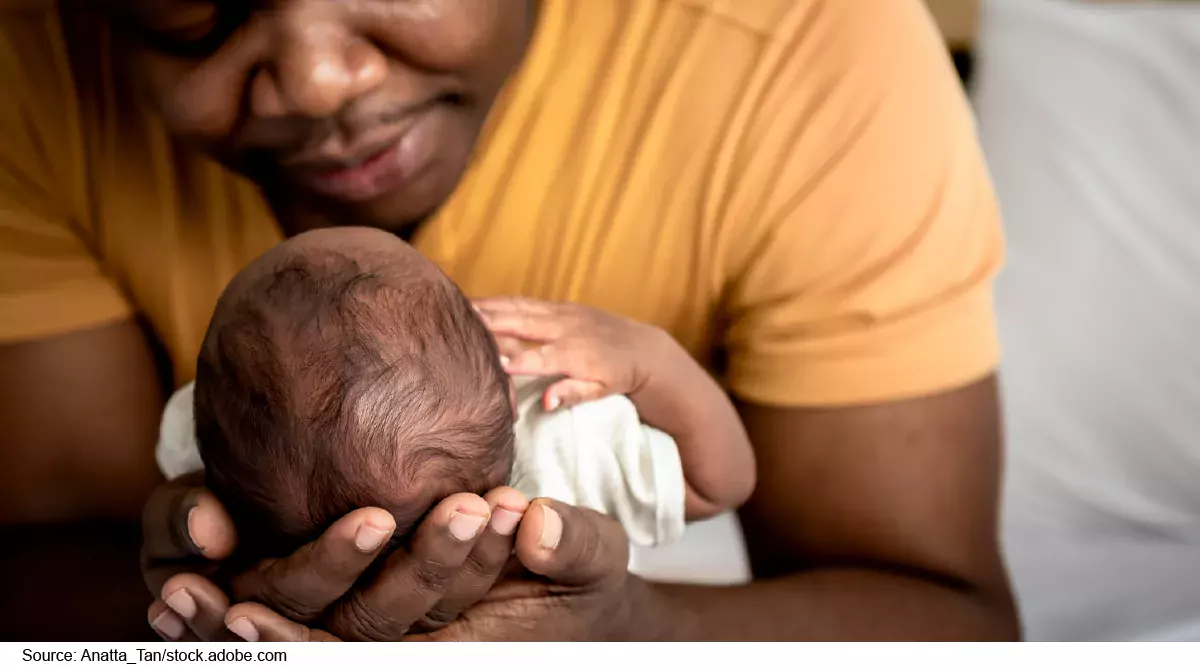 Photo showing a father cradling a new born baby in his arms.