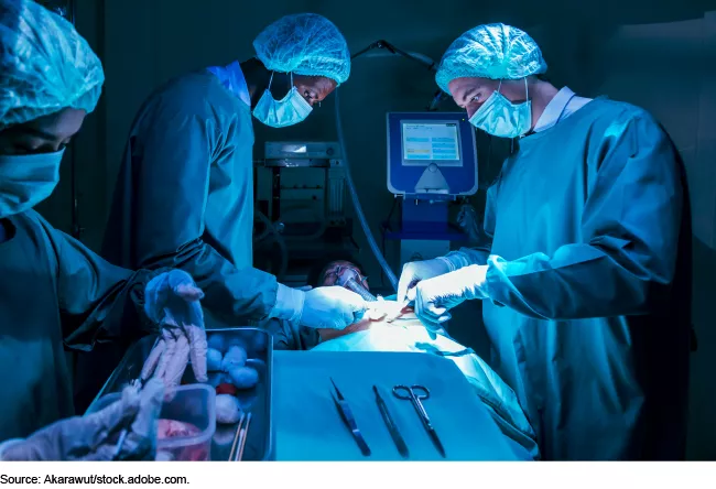 Doctors and nurses in scrubs and masks performing surgery on a patient.