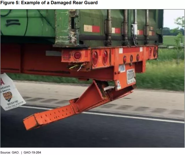 closeup image of a damanged underride gaurd on a dump truck.  The gaurd is bent under the rear of the truck.