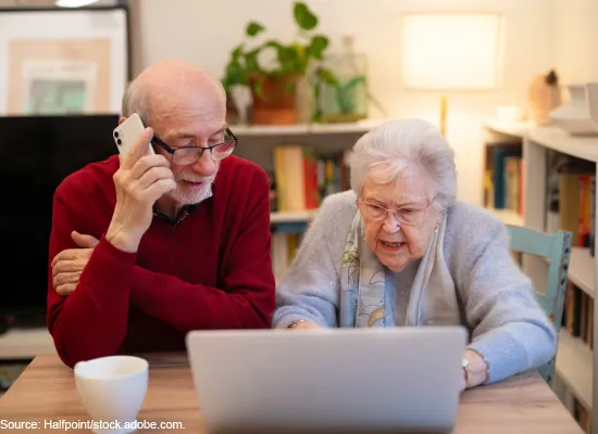 A photo of an elderly woman using a laptop and an elderly man talking on a cell phone.