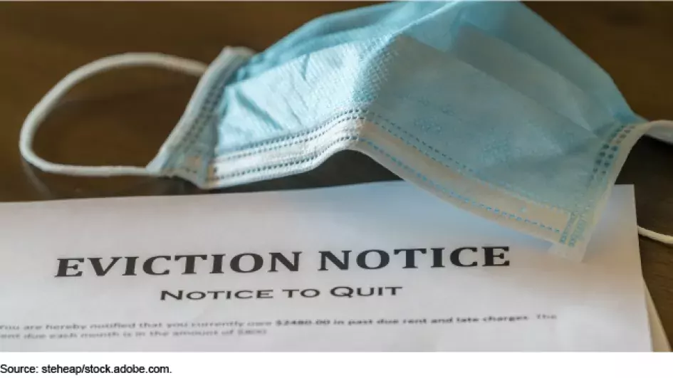 Photo showing a eviction notice with a COVID mask next to it.