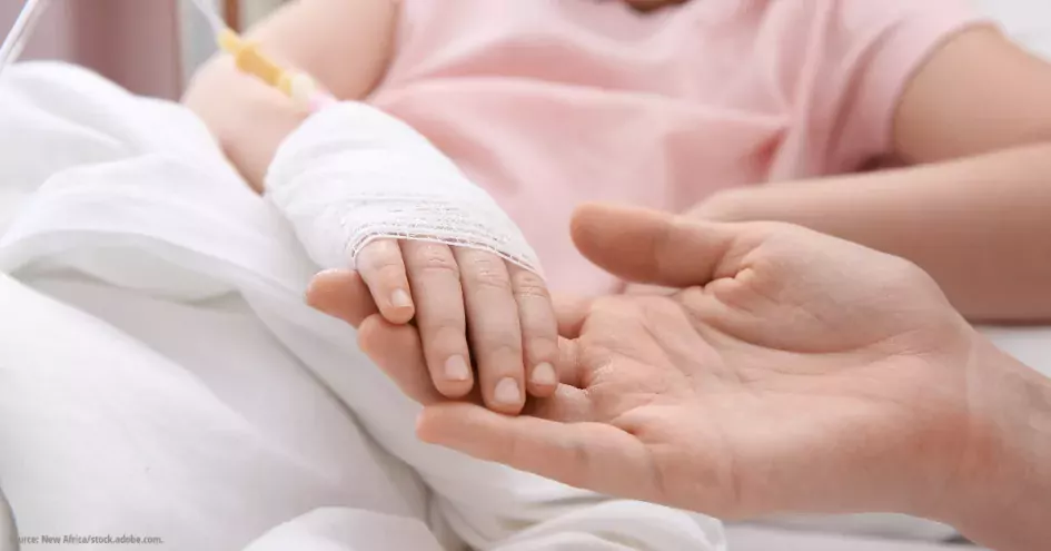 Photo showing a child with an IV in her arm holding hands with an adult, maybe a parent or medical worker