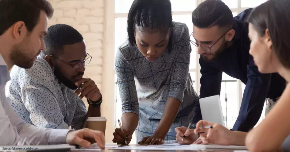 A Black woman surrounded by other office workers.