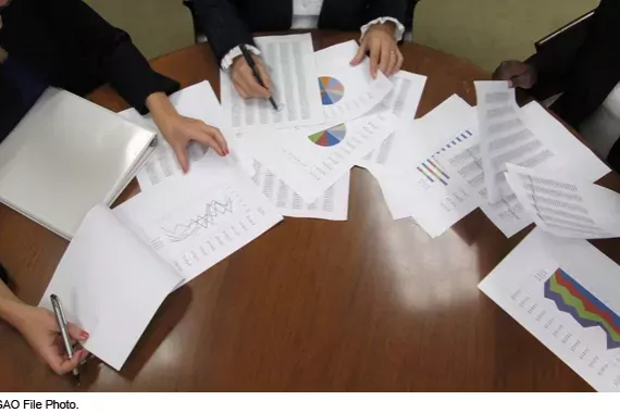 Photo showing a group of workers looking over charts