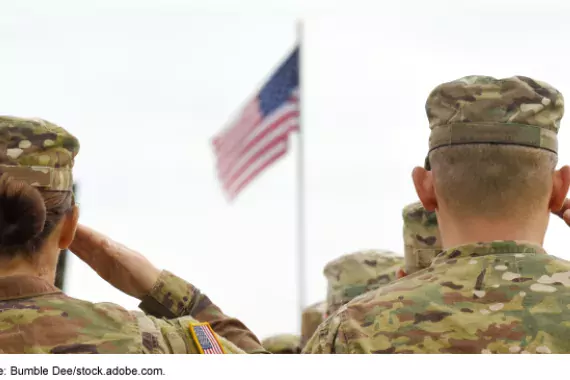 Photo showing military servicemembers saluting a U.S. flag