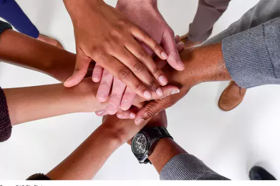 Photo of a huddle of hands representing diverse group