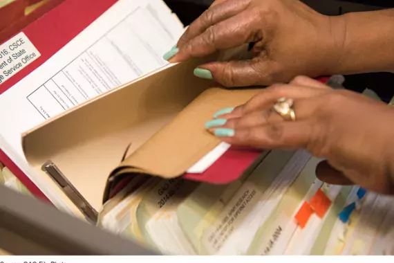 Photo showing someone looking through files on government contracts