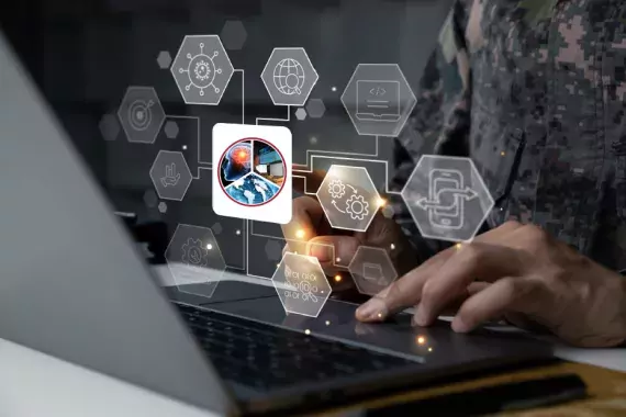 Photo showing a military servicemember at a laptop computer with safety icons floating around him.