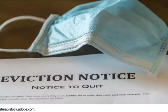 Photo showing a eviction notice with a COVID mask next to it.