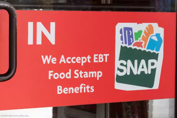 The door to a store with a sign that reads "We accept EBT Food Stamp Benefits--SNAP"