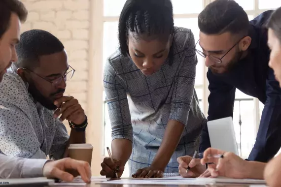 A Black woman surrounded by other office workers.