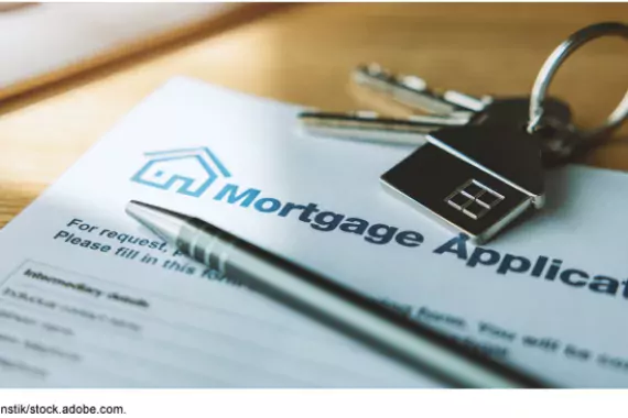 Stock art image showing a mortgage application on a desk with house keys and a pen sitting on top.