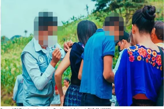 Photo showing a medical worker injecting a COVID vaccine into a woman's arm with others standing by awaiting vaccinations.