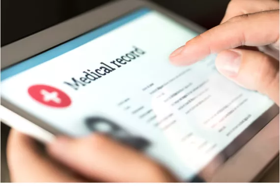 A person holding a tablet showing medical records.