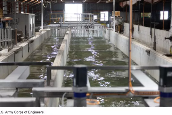 Two large water chambers separated by concrete walls, in a warehouse-type space with pipes and machinery.