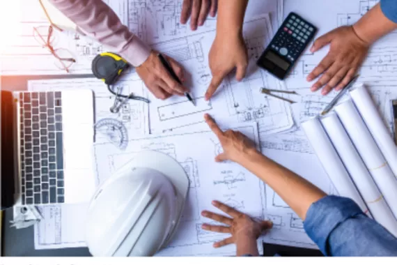 Overhead view of people pointing to technical drawing