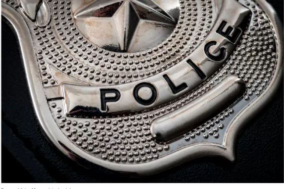 Close-up of a shiny, silver police badge against a black background.