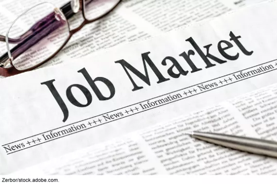  A newspaper with the headline Job Market, with a silver pen and a pair of eyeglasses on top of the paper