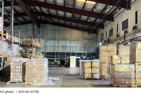 The inside of a cargo warehouse with boxes on pallets stacked on the floor and on shelves. 