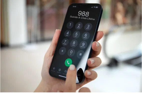 A cellphone in a hand with the 988 Suicide and Crisis Lifeline number on top.