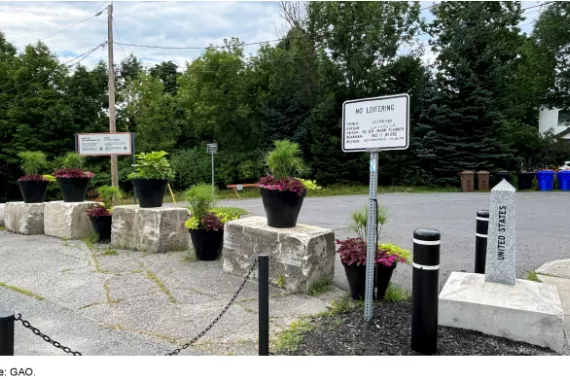 A row of flowerpots atop concrete blocks alongside a small stone obelisk marker that says United States