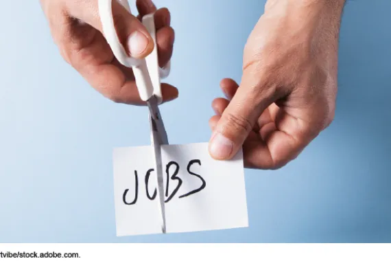 Close-up of a person cutting the word jobs on paper with scissors