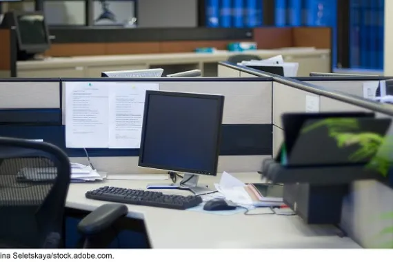 An empty cubicle with a computer in it.